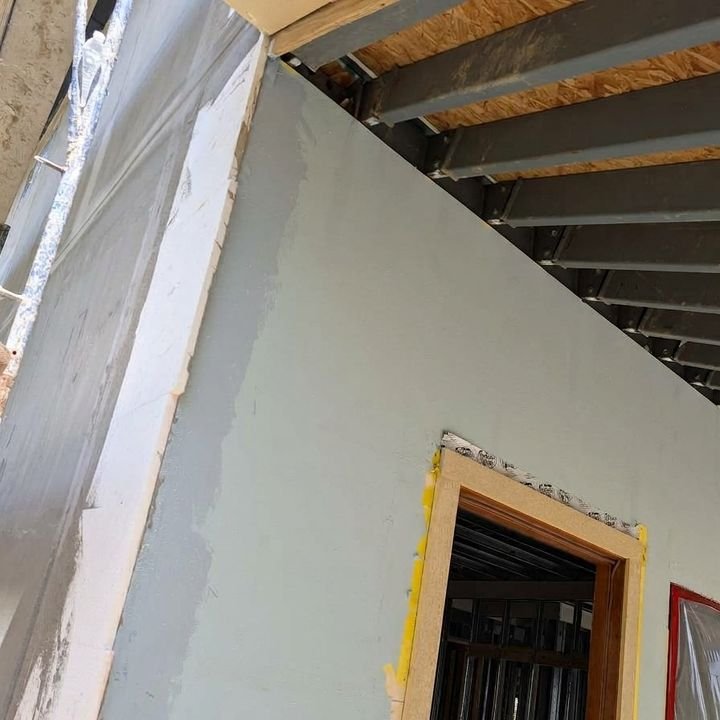 Sheathed and sealed exterior wall under bolted steel framing